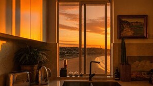 Cozinha com vista para o pôr do sol, pia, torradeira, cafeteira e um cacto.