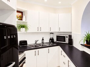 A kitchen with white cabinets, a black countertop, a microwave, a toaster, and a blender.