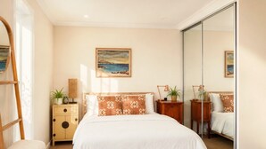 A bedroom with a bed, bedside tables, a mirror, a painting, and a view of the sea. - ★ Sub-Penthouse Beach View ★ by Sydney Dreams ★ (Bondi Beach)