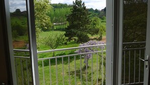 A room with a sliding glass door leading to a balcony with a metal railing.