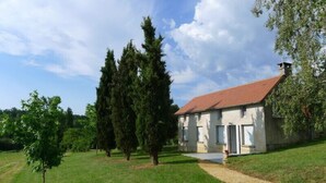 A single-story building with a red-tiled roof, surrounded by a grassy area and trees.