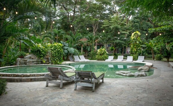 A pool area with lounge chairs and a stone wall.