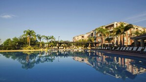 A hotel with a pool reflecting palm trees and a building with balconies. - Elegant and Spacious 3BD Town Home With CDC Standards - Close to Convention Center #3vc007 (Orlando)
