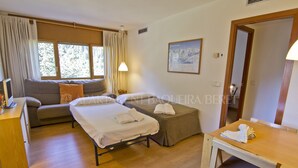 Una habitación de hotel con cama, sofá, mesa y ventana con cortinas.