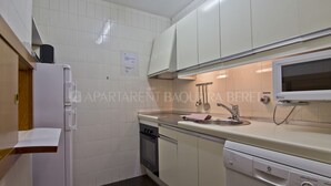 Una cocina con armarios blancos, horno empotrado, lavavajillas y microondas.