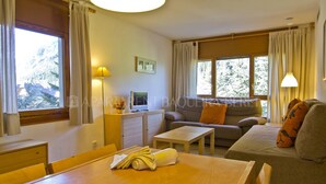 Una sala de estar acogedora con un sofá, una mesa con una toalla enrollada, un televisor y una lámpara.