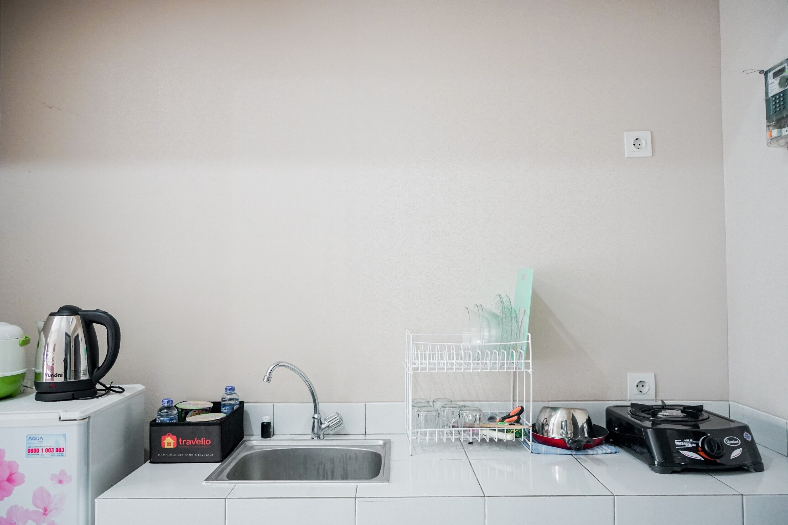 Una kitchenette compacta con lavamanos, tetera, tostadora y artículos de viaje.