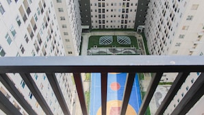 A high-rise building with multiple balconies and a basketball court visible through the gaps. - 2BR Apartment for 4 Pax at Ayodhya Residences (Tangerang)