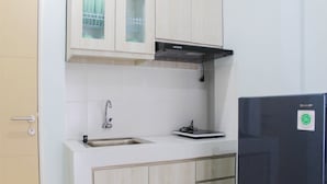 A kitchen with white cabinets, a stainless steel sink, a black range hood, and a Sharp refrigerator. - 2BR Apartment for 4 Pax at Ayodhya Residences (Tangerang)
