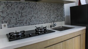 Een keuken met een gasfornuis, een spoelbak en een spatwand van kleine tegels.