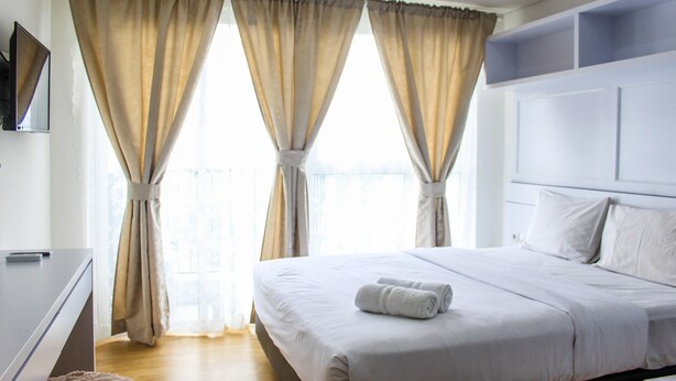 Een hotelkamer met een groot bed, een flatscreen televisie en gordijnen voor de ramen.