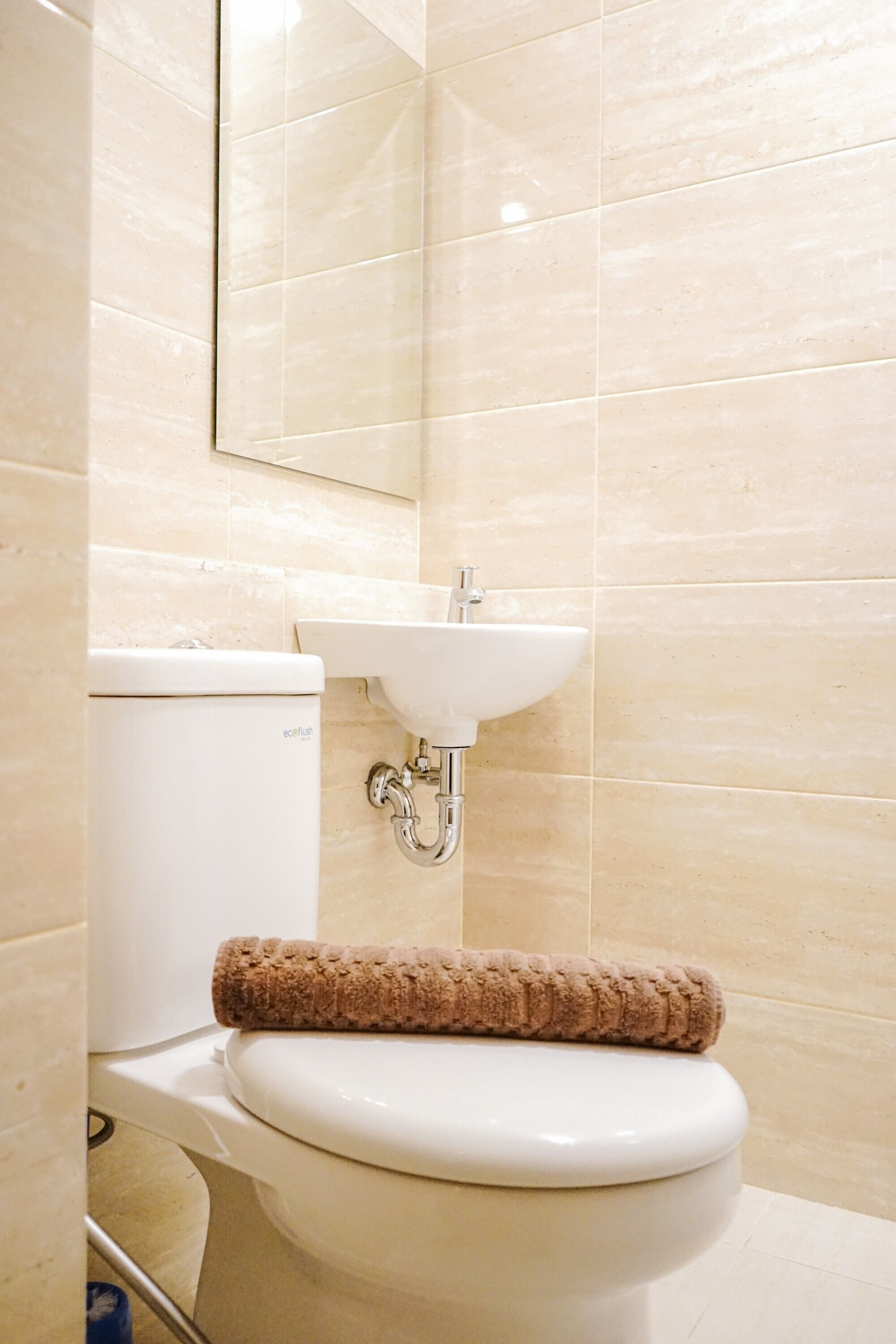 A bathroom with a toilet, sink, and a towel on the toilet.