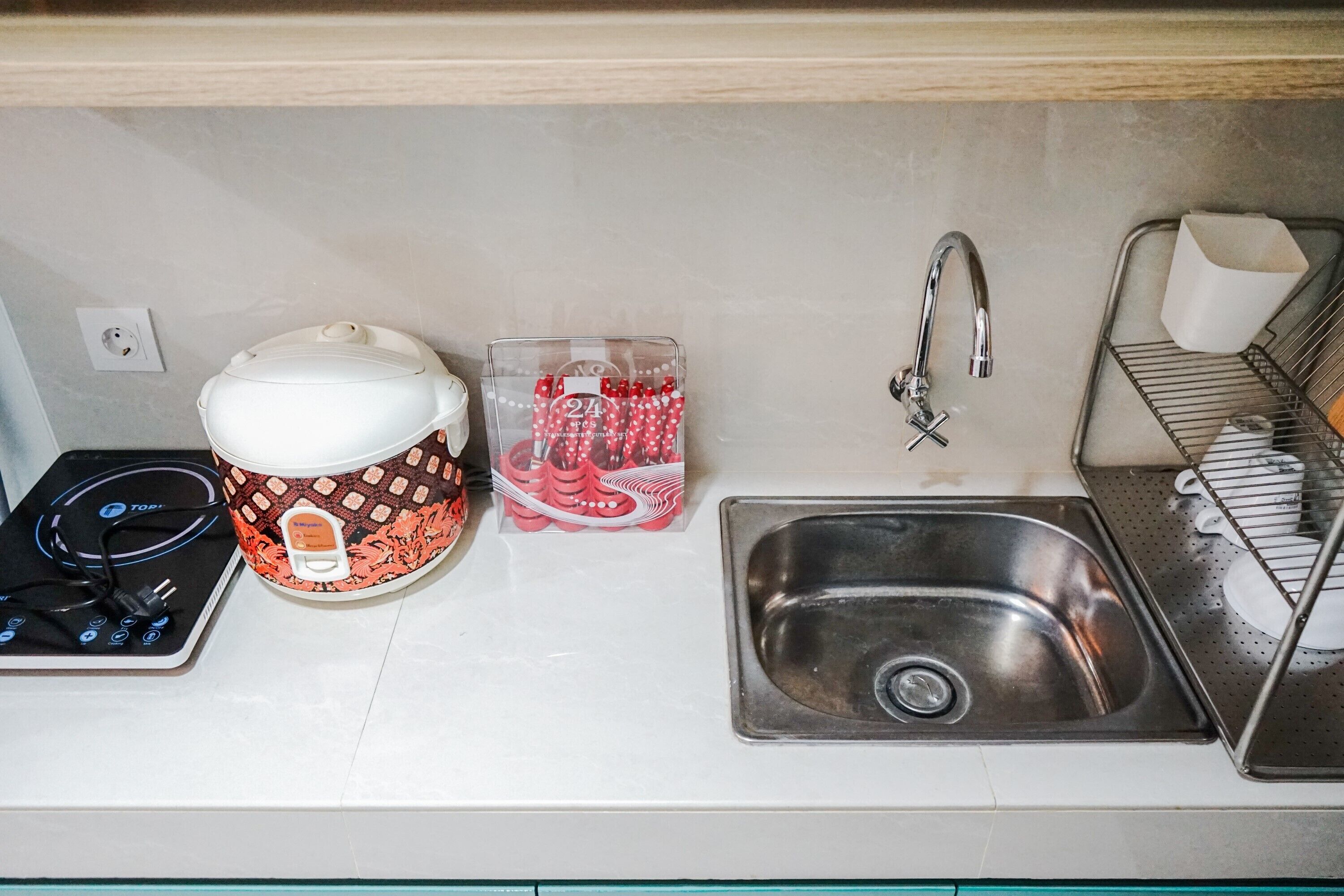 A kitchen with a stove, a coffee maker, a sink, and a dish rack.