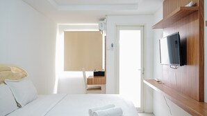 Une chambre d’hôtel avec un lit, un téléviseur fixé au mur, une armoire en bois et une fenêtre donnant sur un beau paysage.