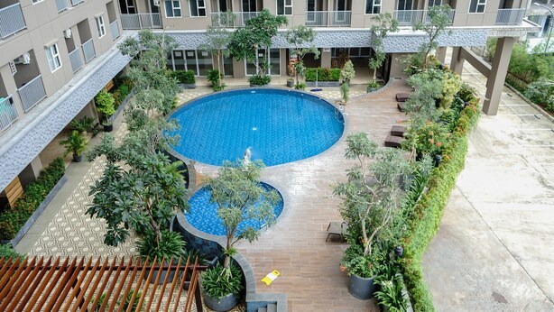 Une piscine sur le toit, entourée de plantes en pot et agrémentée d’un espace salon extérieur.