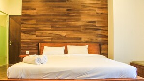 A neatly made bed with white linens and rolled towels, a wooden headboard, and a wooden nightstand with a green tray. - Homey and Warm 3BR Apartment at Ambassade Residences (Jakarta)