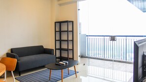 A living room with a sofa, a coffee table, and a bookshelf. - Homey and Warm 3BR Apartment at Ambassade Residences (Jakarta)