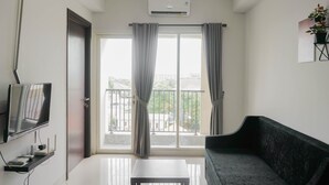 Una sala moderna con una televisión de pantalla plana, un sofá y un balcón con cortinas.