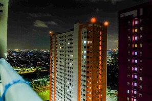 A high-rise building with multiple floors, large windows, and a view of a cityscape at night. - Pleasant 2BR Apartment at Green Pramuka near Mall (Jakarta)