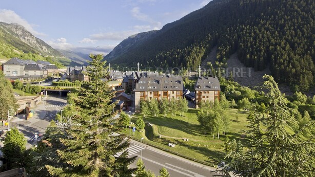 Un hôtel comprenant plusieurs bâtiments, un parking et offrant une vue sur un paysage montagneux.