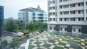 A modern building with a rooftop terrace featuring a checkered pattern and a glass walkway.