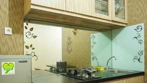 A kitchen with wooden cabinets, a black countertop, a stainless steel sink, and a Sharp refrigerator.