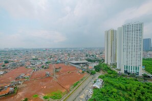 A high-rise building with a modern design, surrounded by a mix of residential and undeveloped land. - Brand New and Cozy 2BR Kuningan Place Apartment (Jakarta)