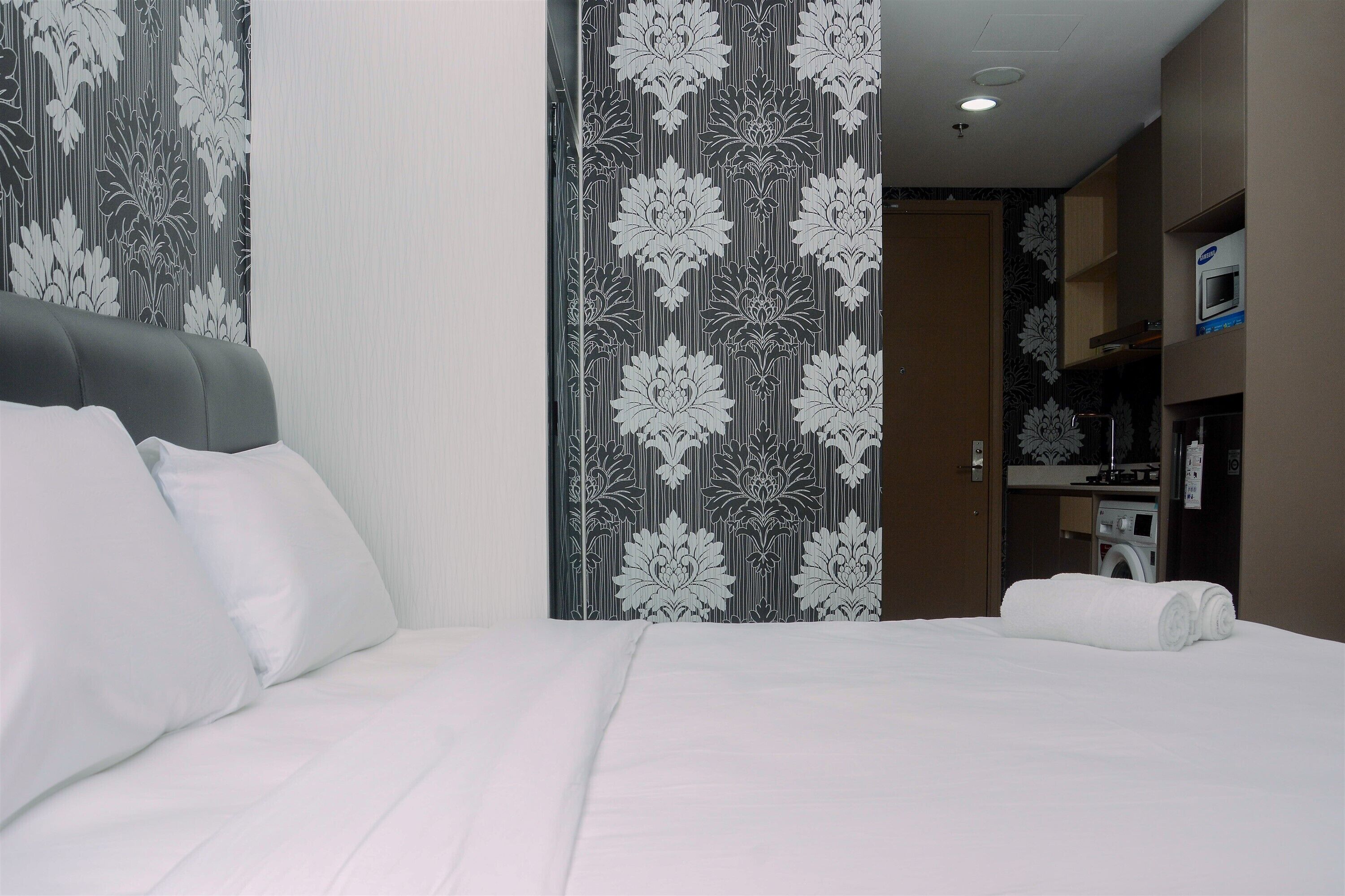 Ein Hotelzimmer mit Bett, Kissen, einem Kleiderschrank und einer Waschmaschine.
