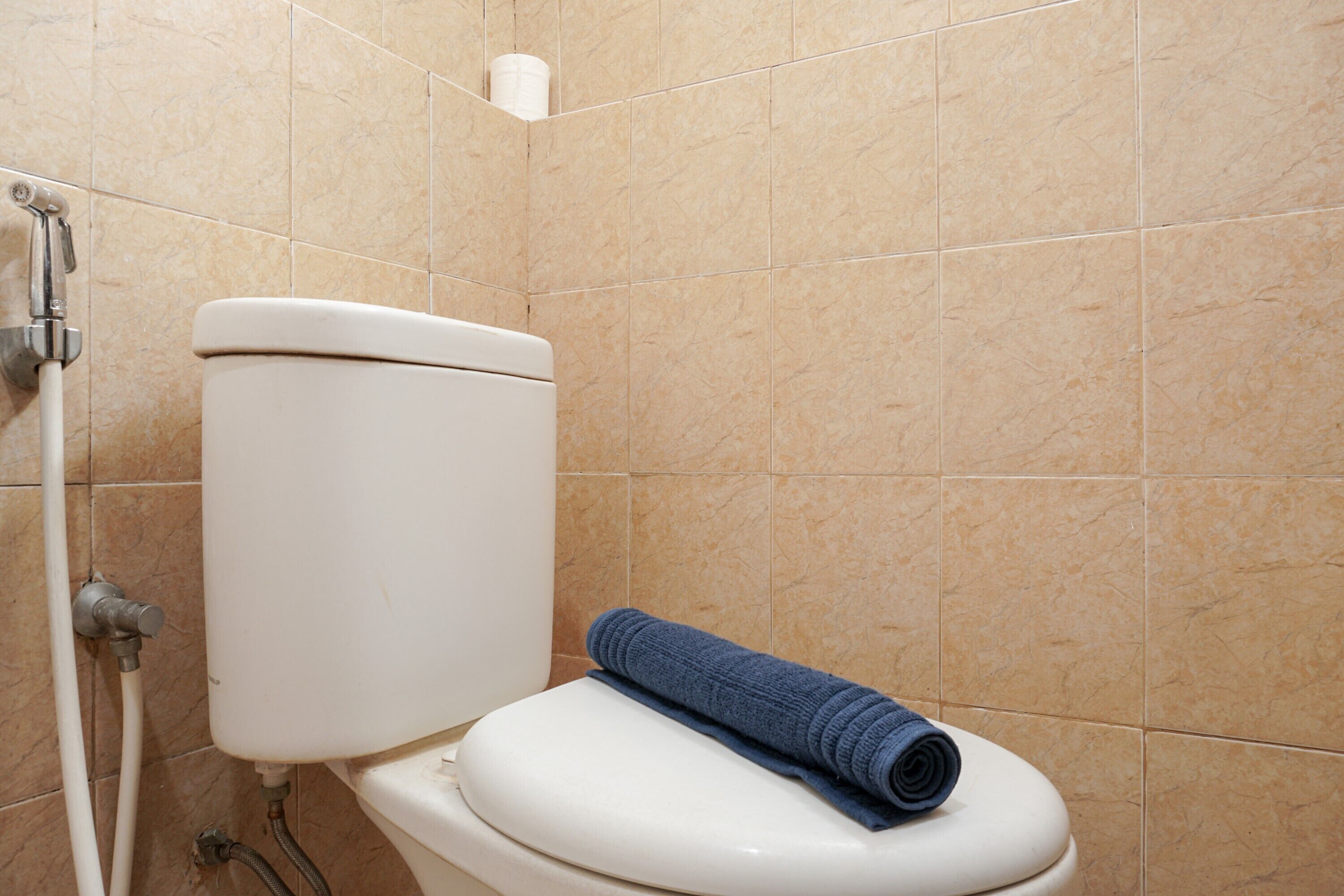 Un baño con inodoro, una toalla y un portaescobillas en la pared.