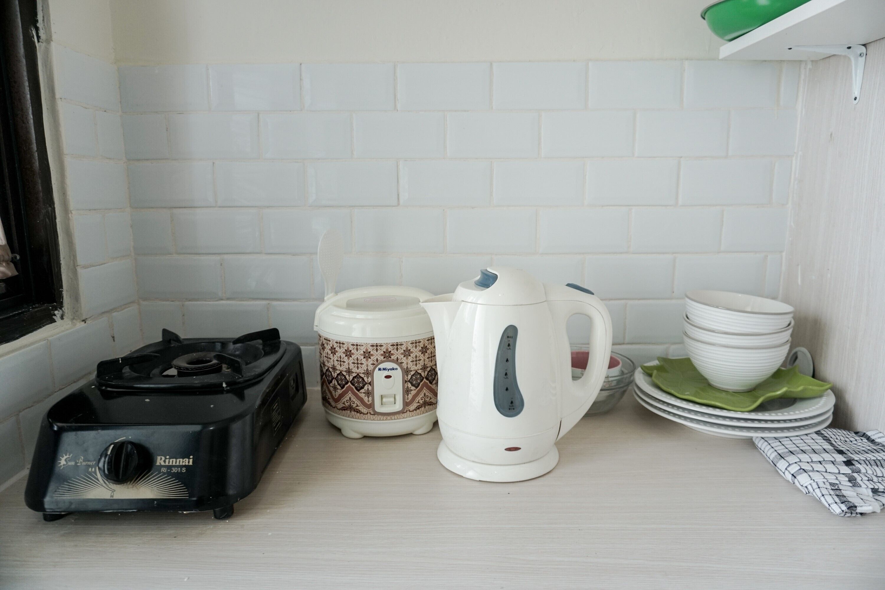 A kitchen with a gas stove, a rice cooker, and a kettle.
