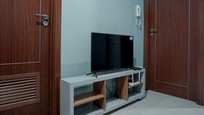 A room with a wooden wardrobe, a white console table with a flat-screen TV, and a telephone mounted on the wall. - Fully Furnished 1BR Apartment at Vittoria Residence (Jakarta)