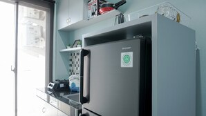 A kitchen with a black refrigerator, a microwave, and a toaster. There is a window with a view of buildings outside. - Fully Furnished 1BR Apartment at Vittoria Residence (Jakarta)