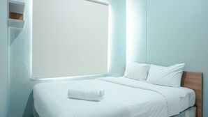 A modern hotel room with a large bed, a wooden headboard, and a window with blinds. - Fully Furnished 1BR Apartment at Vittoria Residence (Jakarta)