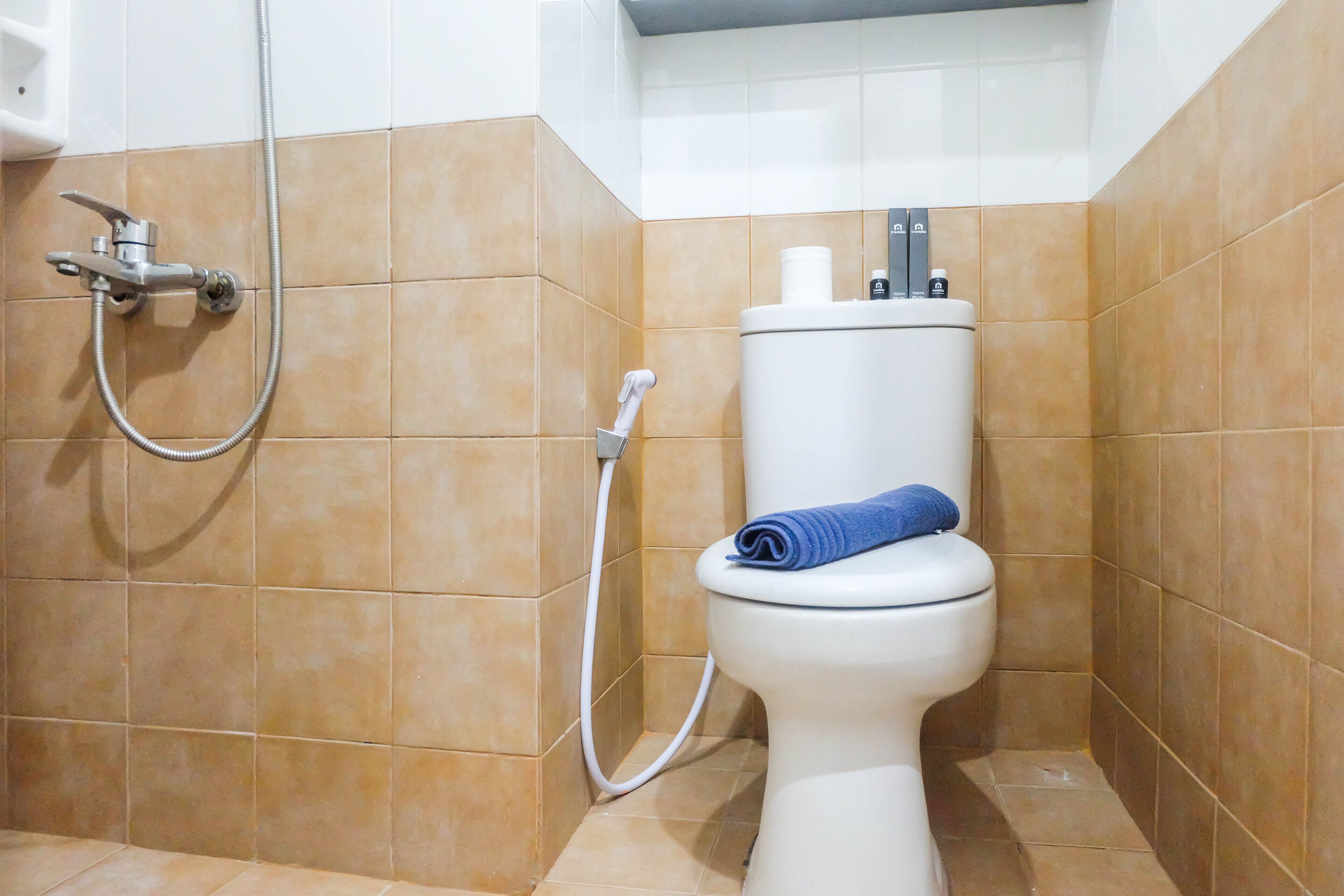 Une salle de bain équipée de toilettes, d’une douche et d’un porte-serviettes.