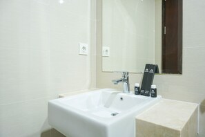 A bathroom with a white sink, a mirror, and two toothbrushes on the counter.