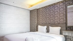 Ein ordentlich bezogenes Bett mit weißen Leinentüchern und zwei zusammengerollten Handtüchern, ein hölzernes Kopfteil und eine Wand mit gemustertem Wandpapier.