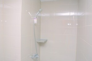 A shower with a handheld showerhead and a wall-mounted faucet. - Modern 3BR Apartment at Springhill Terrace Residence (Jakarta)
