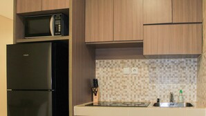 Cozinha com geladeira preta, micro-ondas e painel de azulejos.