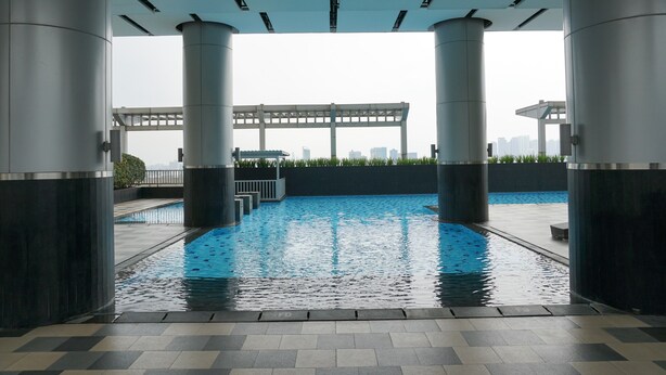 Piscina no terraço com vista para o horizonte da cidade, cercada por colunas imponentes e uma galeria coberta.