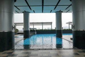 Ein Dachpool mit Blick auf die Skyline der Stadt, umgeben von hohen Säulen und einem überdachten Gang.