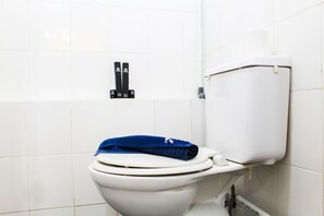 A white toilet with a blue towel on the seat and a toilet paper holder on the wall. - Stylish and Posh 1BR Gading Nias Apartment (Jakarta)