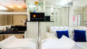 A modern hotel lobby with a glass partition, a minibar, and a seating area with white chairs and a white sofa with blue cushions. - Posh 2BR Apartment at Bassura City near Shopping Mall (Jakarta)