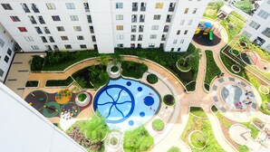 A high-rise residential building with a rooftop garden, playgrounds, and a circular water feature. - Posh 2BR Apartment at Bassura City near Shopping Mall (Jakarta)