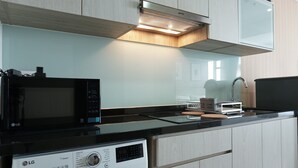 A modern kitchen with a microwave, dishwasher, and a sink. - Cozy and Tranquil Studio Menteng Park Apartment (Jakarta)