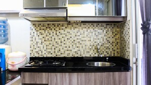 Een kleine keuken met een gasfornuis, een spoelbak en een betegelde spatwand.