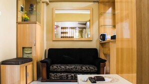A compact living space with a sofa, a small table, and a cabinet. - Comfortable and Fully Furnished 1BR Green Pramuka Apartment (Jakarta)