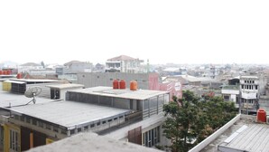 A cityscape with multiple buildings, including a prominent structure with a red roof and a satellite dish on the rooftop. - Minimalist 3BR Gateway Cicadas Ahmad Yani Apartment (Bandung)