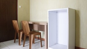 A room with a wooden desk and two wicker chairs. - Minimalist 3BR Gateway Cicadas Ahmad Yani Apartment (Bandung)