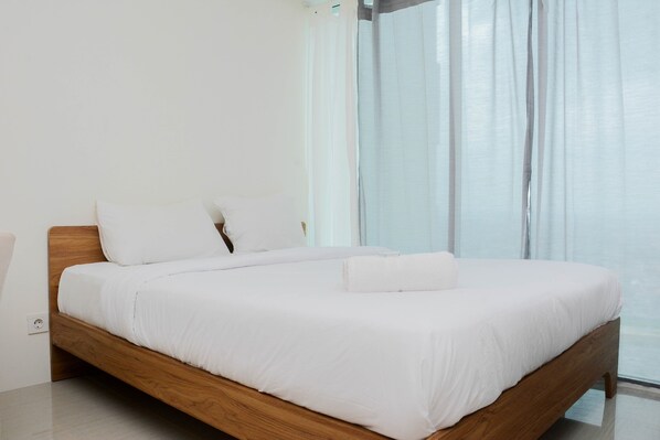 Relax in a serene bedroom with a comfortable bed, wooden headboard, and large window.