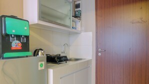 A compact kitchen with a water dispenser, a kettle, and a microwave on the countertop. - New Furnished Studio Apartment at Gunung Putri Square (Gunung Putri)